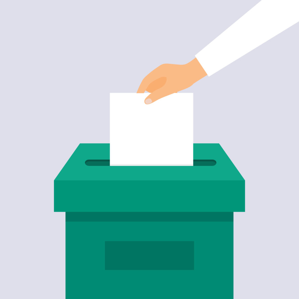 Hand puts voting ballot in ballot box. Election concept.